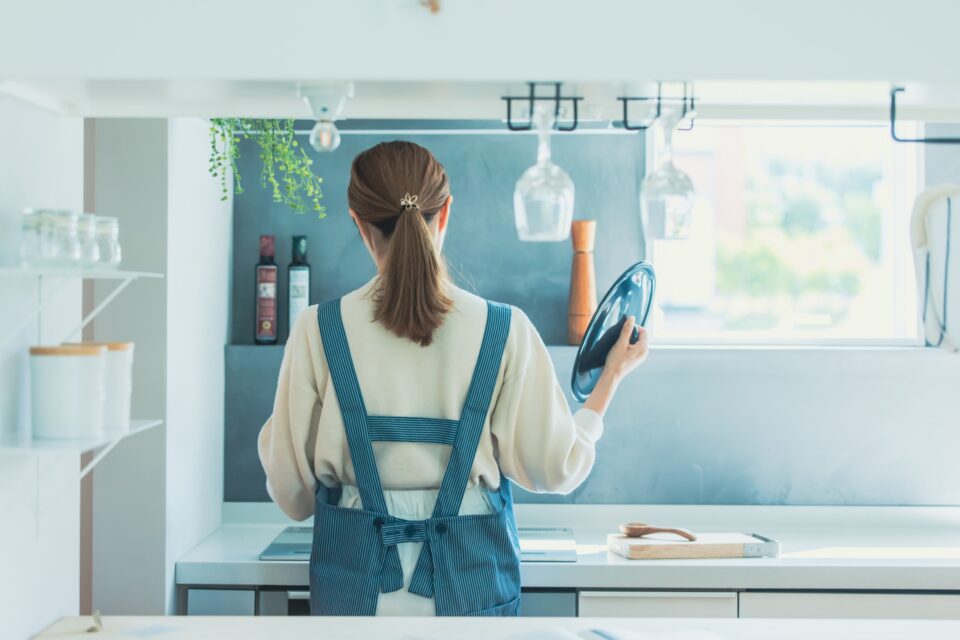 キッチンで鍋のふたを開ける女性