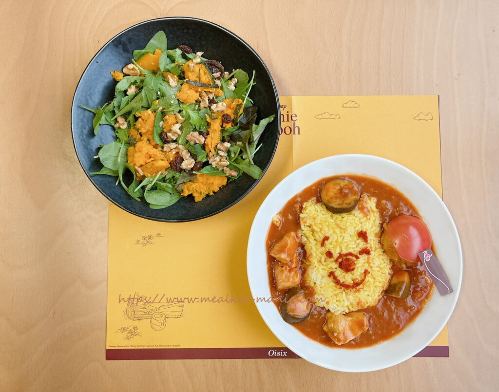 くまのプーさんのトマトカレーとサラダが特製ランチョンマットの上にある